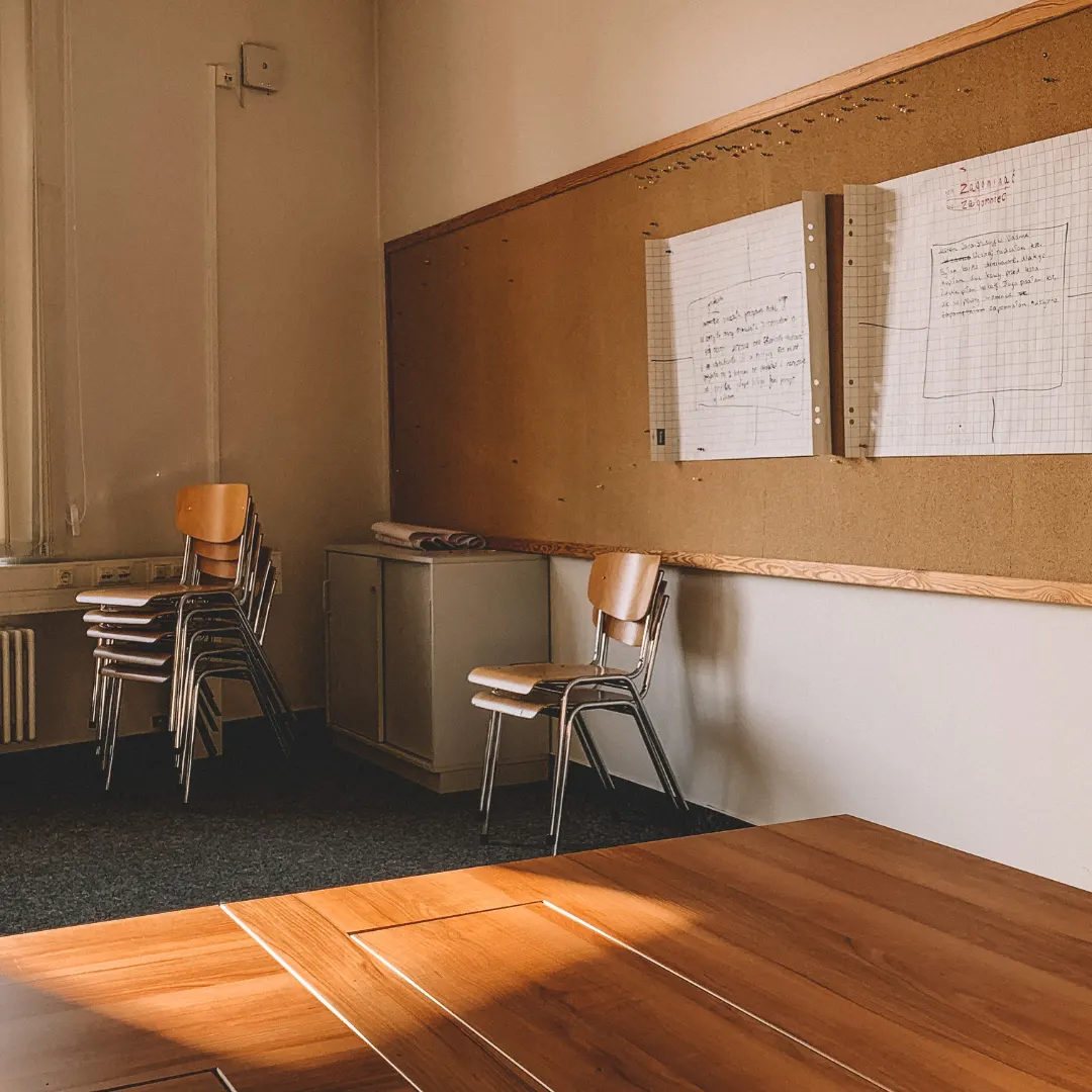Training room with stacked chairs and handwritten flipcharts pinned to a noticeboard